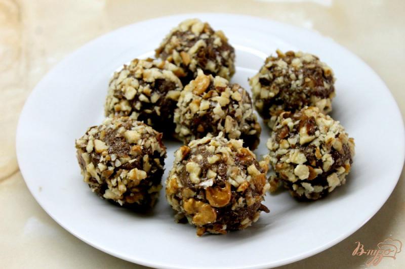 Фото приготовление рецепта: Сладкие шарики из шоколадного бисквита с масляным кремом и орехами шаг №7