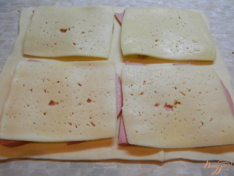 Фото приготовление рецепта: Закуска из слоеного теста колбасы и сыра шаг №3